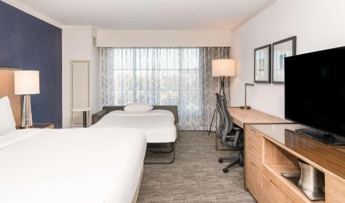 a hotel room with two beds and a flat screen tv at Hilton Columbus/Polaris in Columbus