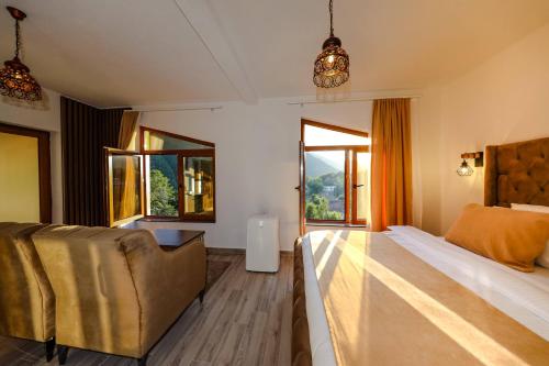 a bedroom with a bed and a couch and windows at Chalet Kujta in Peje