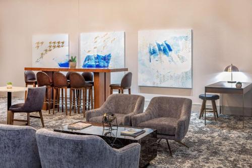 a waiting room with chairs and a bar with paintings at Hilton Columbus/Polaris in Columbus