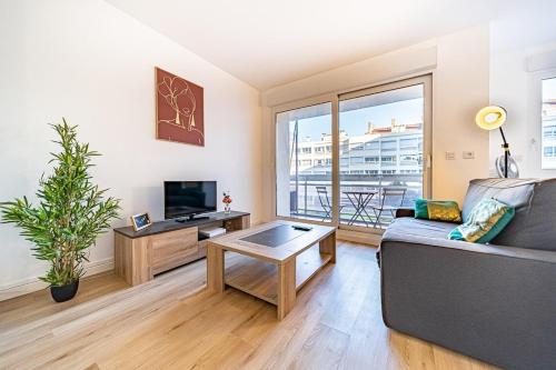 uma sala de estar com um sofá e uma televisão em Le petit Massena-cosy 2 pers balcon- Part Dieu em Lyon
