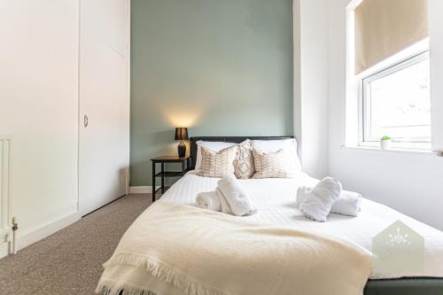um quarto branco com uma grande cama branca com almofadas em Cosy 3 Bedroom house in Wigan em Bickershaw