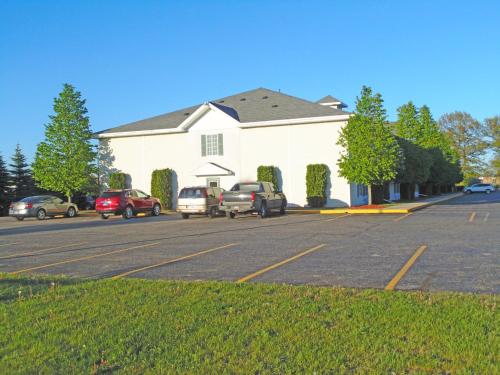 a parking lot with cars parked in front of a building at American Inn and Suites Houghton Lake in Houghton Lake