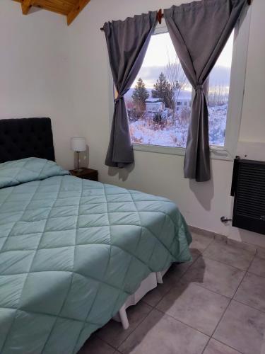 a bedroom with a large bed and a window at Cabaña Maca Tobiano in El Calafate