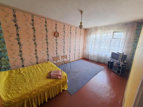um quarto com uma cama amarela e uma televisão em 1-но комнатная квартира на Бульваре Вечернем em Krivoy Rog
