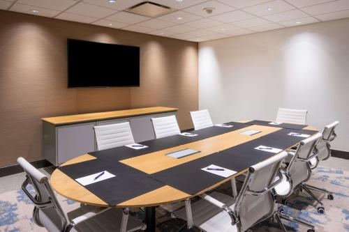a conference room with a table and chairs and a flat screen tv at The Bethesdan Hotel, Tapestry Collection by Hilton in Bethesda