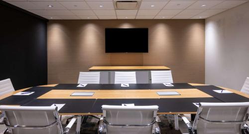 a conference room with a table and a flat screen tv at The Bethesdan Hotel, Tapestry Collection by Hilton in Bethesda