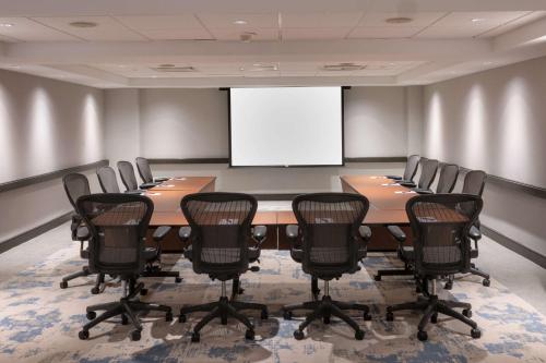 a conference room with a table and chairs and a white screen at The Bethesdan Hotel, Tapestry Collection by Hilton in Bethesda