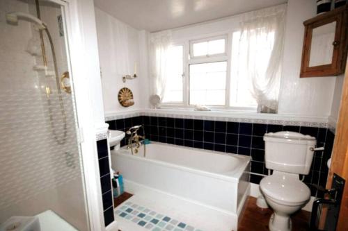 a bathroom with a tub and a toilet and a sink at Quirky City-Centre Cottage in Exeter