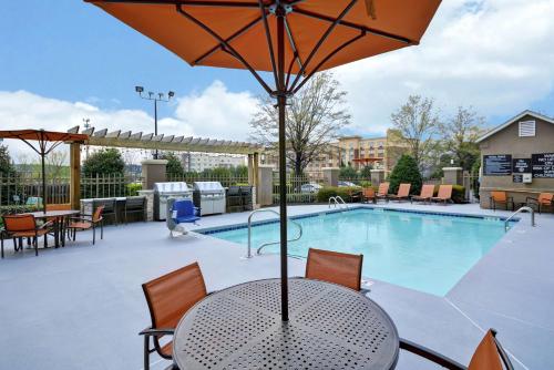 a patio with a table with an umbrella and a pool at Homewood Suites by Hilton Augusta in Augusta