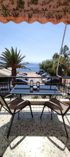 a table with chairs and an umbrella on the beach at Sea side apartment in Loutraki