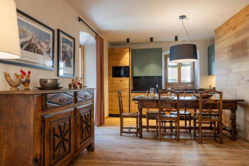 Il comprend une cuisine et une salle à manger avec une table et des chaises en bois. dans l'établissement Maison Luboz - Courmayeur, à Courmayeur