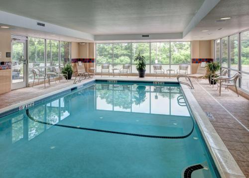 a swimming pool in a hotel with tables and chairs at Hampton Inn & Suites Westford-Chelmsford in Westford