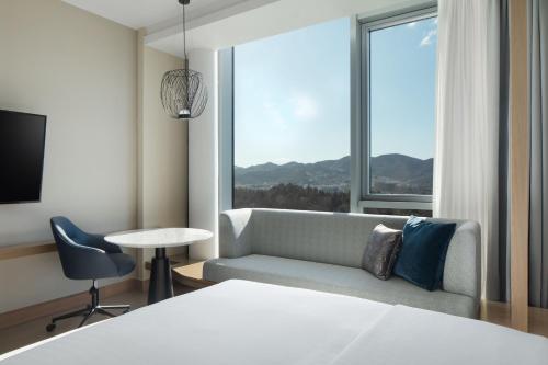een slaapkamer met een bank en een groot raam bij Tirana Marriott Hotel in Tirana