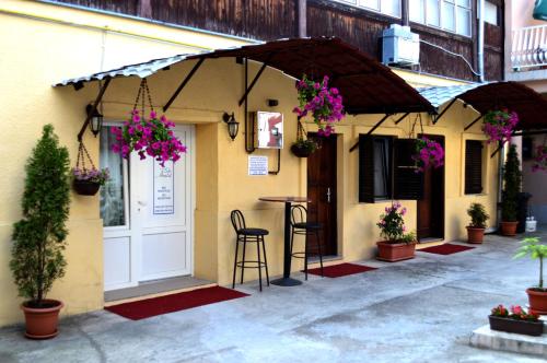 - un bâtiment avec une terrasse couverte, un bar et des fleurs dans l'établissement Rooms Aračić, à Slavonski Brod