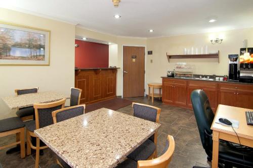 a waiting room with tables and chairs and a kitchen at Valley Inn Shakopee in Shakopee