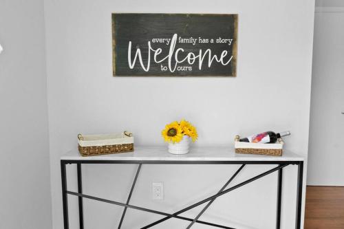 a table with flowers and a welcome sign on the wall at Stadium Sunflower Miramar home, 3 bd, 2 ba in Miramar