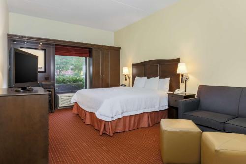 a hotel room with a bed and a couch and a television at Hampton Inn Champaign/Urbana in Urbana