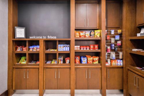 a pantry with wooden cabinets with food on them at Hampton Inn & Suites Legacy Park-Frisco in Frisco