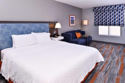 a bedroom with a large white bed and a blue chair at Hampton Inn & Suites Legacy Park-Frisco in Frisco