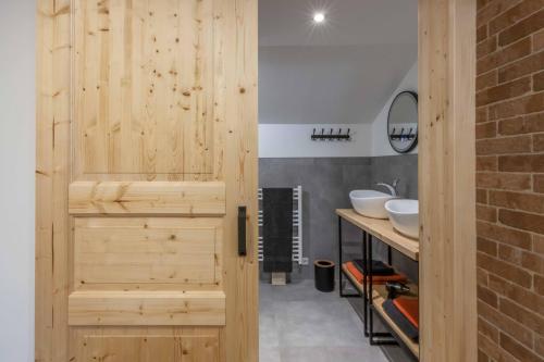 uma casa de banho com uma porta de madeira e 2 lavatórios em Ski-Bike-Apartment Bayerwald em Lohberg