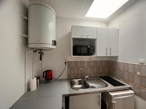 une petite cuisine avec un évier et un micro-ondes dans l'établissement Studio Arc de triomphe - HALA PARIS, à Paris