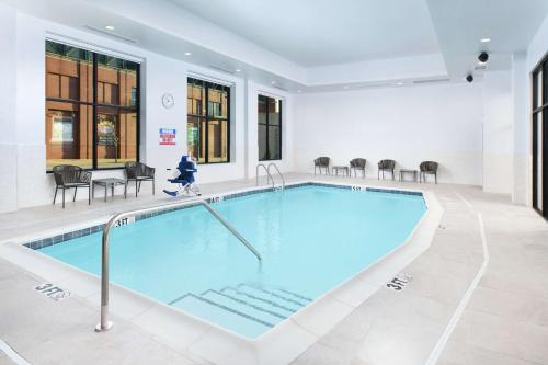 a swimming pool in a building with chairs and a table at Hilton Garden Inn Memphis Downtown Beale Street in Memphis