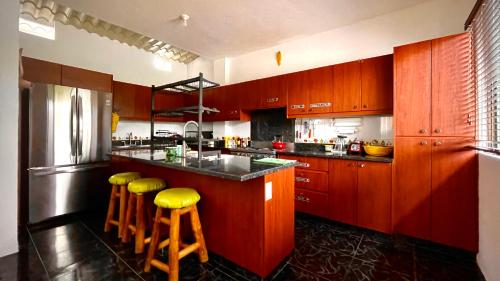 a kitchen with wooden cabinets and yellow stools at Hostal Laurita Beach in Montañita