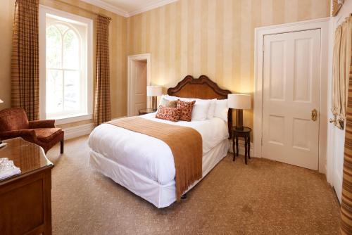 a bedroom with a bed and a chair and a window at Mansion Hill Inn in Madison