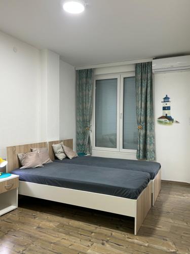 a bedroom with a bed with blue sheets and a window at Adam's Apartment 1 in Kladovo