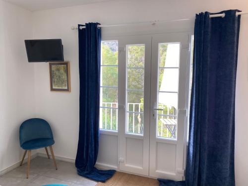 a room with a window with blue curtains and a chair at El nido del Chorro in Málaga