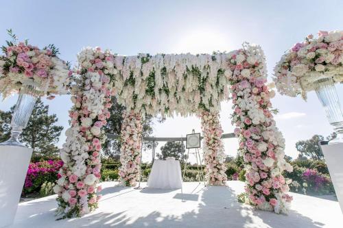 a wedding arch covered in pink and white flowers at Hilton La Jolla Torrey Pines in San Diego