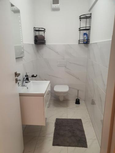 een witte badkamer met een toilet en een wastafel bij Apartament Comfortable Fortuna in Sfântu-Gheorghe