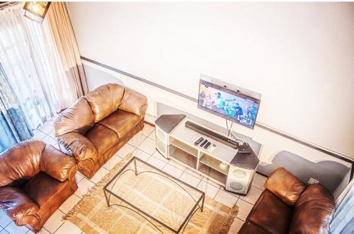 uma sala de estar com mobiliário de couro e uma televisão de ecrã plano em 19 @ Pendleberry em Bela-Bela