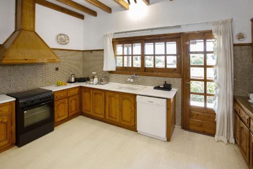 a kitchen with wooden cabinets and a sink and a window at KORALIA MARATHON VILLA in Nea Makri