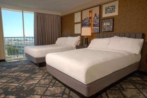 a hotel room with two beds and a balcony at Embassy Suites San Francisco Airport - South San Francisco in South San Francisco