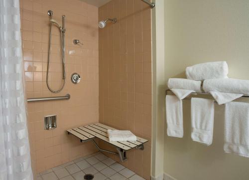 y baño con ducha y toallas en un estante. en Embassy Suites By Hilton Seattle - Tacoma International Airport, en Tukwila
