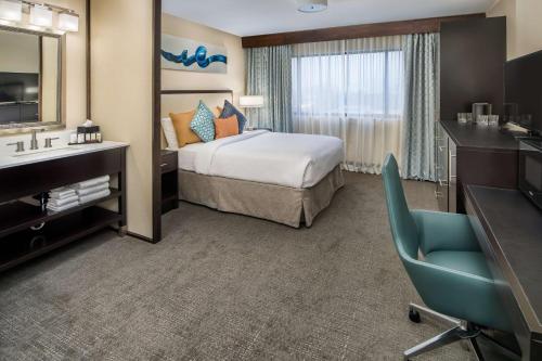 タクウィラにあるEmbassy Suites By Hilton Seattle - Tacoma International Airportのベッド、デスク、シンクが備わるホテルルームです。