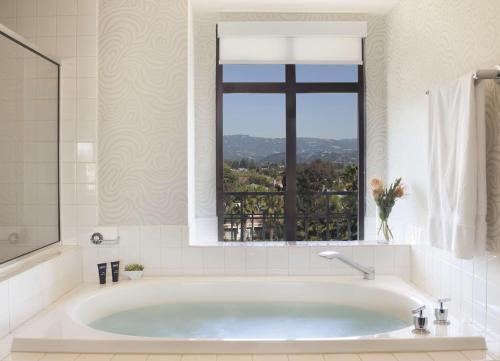 a bath tub in a bathroom with a window at Juniper Hotel Cupertino, Curio Collection by Hilton in Cupertino