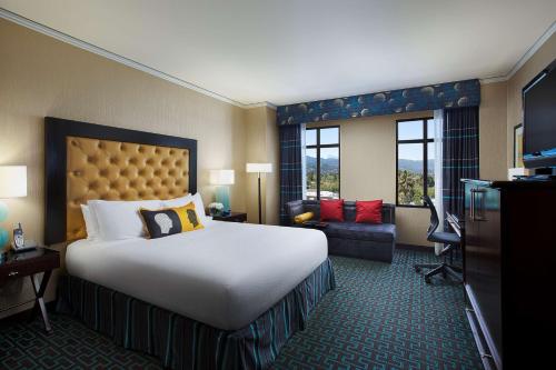 a hotel room with a large bed and a living room at Juniper Hotel Cupertino, Curio Collection by Hilton in Cupertino