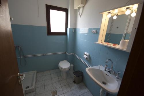 a blue bathroom with a toilet and a sink at Hotel Sevilli in Agios Ioannis Pelio