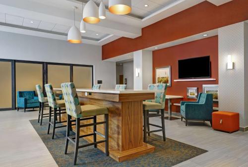 a bar in a waiting room with chairs and a tv at Hampton Inn & Suites Belleville in Belleville