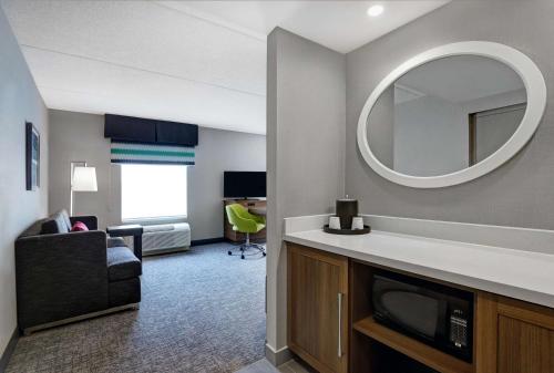 a room with a living room with a mirror and a couch at Hampton Inn & Suites Belleville in Belleville