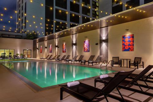 a swimming pool with chairs and a building at Hilton Austin in Austin