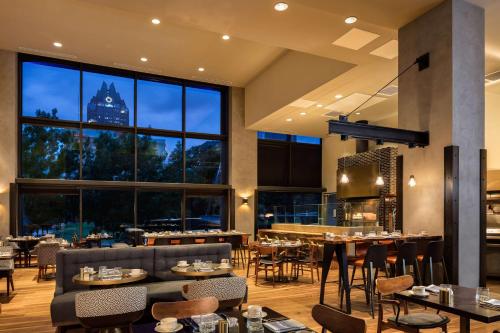 a restaurant with tables and chairs and a large window at Hilton Austin in Austin