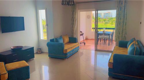 sala de estar con 2 sillas azules y mesa en magnifique appartement de trois chambres avec vue sur le golf et la mer Marina Asilah, en Asilah