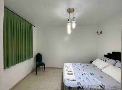1 dormitorio con 1 cama, cortina verde y silla en Amazing apartment in the heart of El jadida, en El Jadida