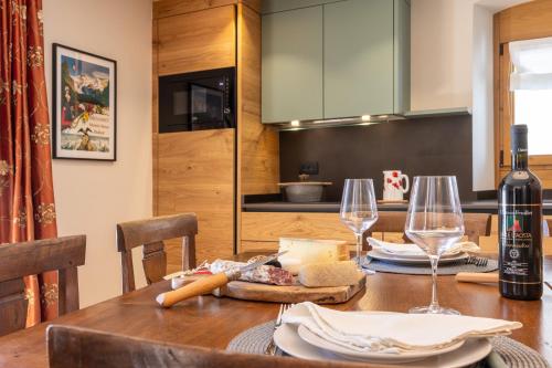 a dining room table with a bottle of wine and glasses at Maison Luboz - Courmayeur in Courmayeur