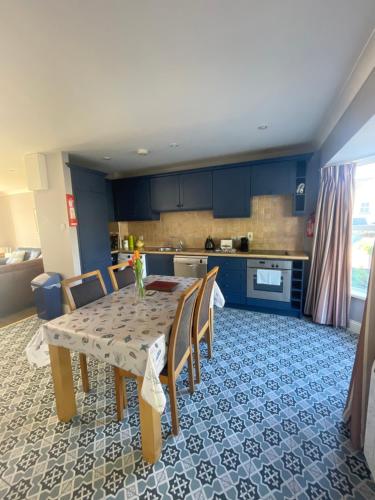 eine Küche mit einem Tisch mit Stühlen und blauen Schränken in der Unterkunft Faithlegg Estate, Mews Holiday Home, Waterford in Waterford