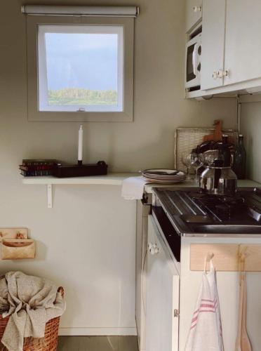 a kitchen with a stove and a sink and a window at Husbåt i småländsk idyll in Ryssby