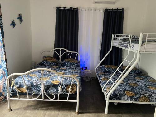 a room with two bunk beds and a window at Kaza Ohana proche de Malendure - maison 8 à 11 personnes in Bouillante